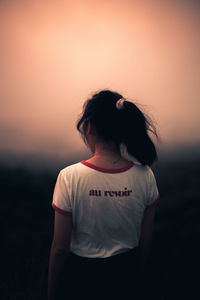 Woman standing on field against sky during sunset