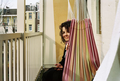 Smiling young woman standing against curtain