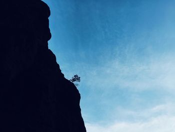 Low angle view of silhouette rock formation against blue sky