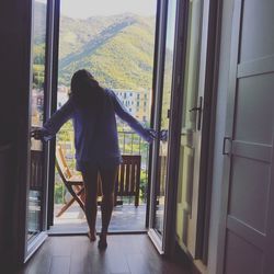 Rear view of woman standing by window