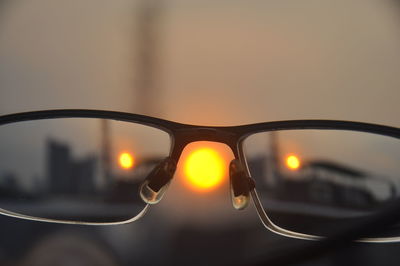 Close-up of sunglasses against sky during sunset