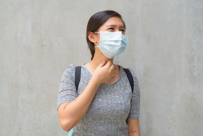 Portrait of young woman standing against wall