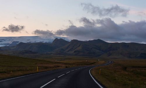 Scenic view of road by mountains against sky