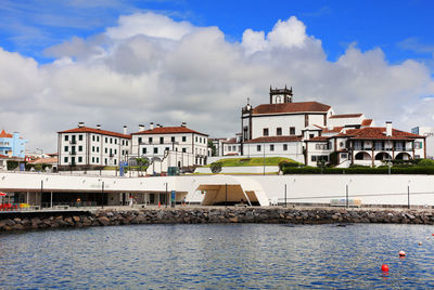 Buildings by sea against sky