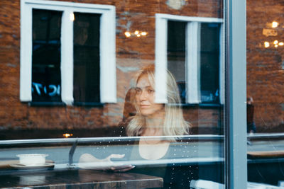 Portrait of woman looking through window