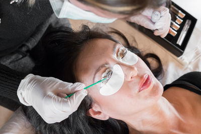 High angle view of beautician applying beauty product on woman face