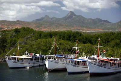 Boats moored in river by mountains against sky