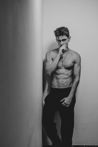 Portrait of shirtless handsome man standing against wall