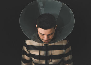 Close-up of man wearing protective collar against black background