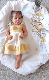 Portrait of cute baby girl lying on bed at home