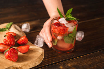 Cropped image of hand holding fruit on table