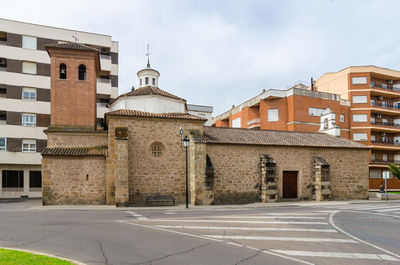 Road by buildings against sky in city