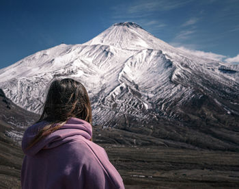 Rear view of woman looking at snowcapped mountain against sky