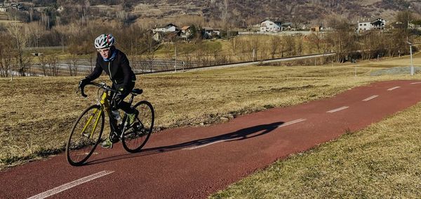 Low section of man riding bicycle on field