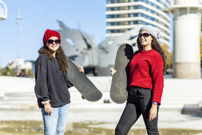 Teenage girls with skateboard standing in city