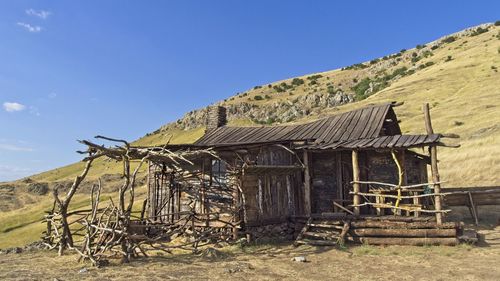 Old abandoned house by building against sky