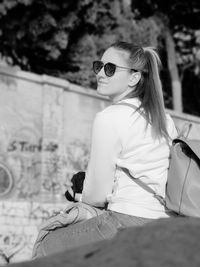 Woman wearing sunglasses sitting outdoors