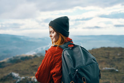 Young woman looking at mountains against sky