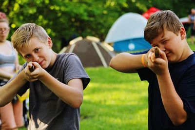 Portrait of boy aiming with weapons on field