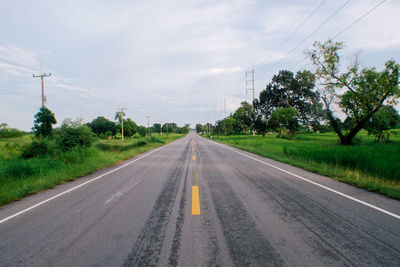 Road by trees against sky