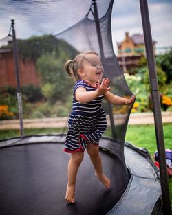 Full length of cute girl playing on trampoline