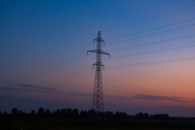 Low angle view of silhouette electricity pylon on field against sky during sunset