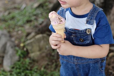 Midsection of boy holding ice cream while standing outdoors