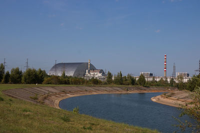 Scenic view of river by buildings against clear blue sky