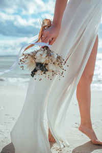 Tender bride holding a wedding bouquet in her hands on the background of the sea.