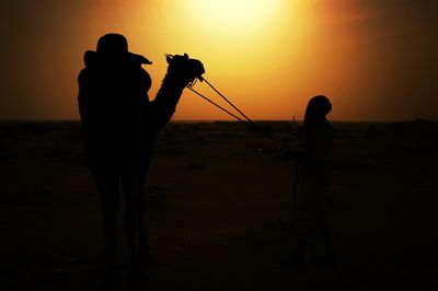 Silhouette of people on beach at sunset