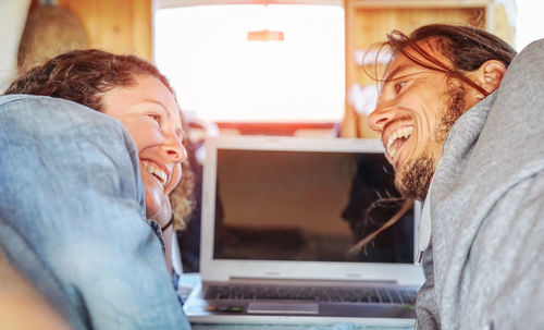 Happy couple looking at each other by laptop in motor home