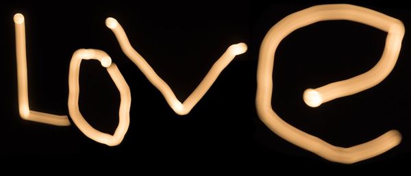 Close-up of illuminated lamp over black background