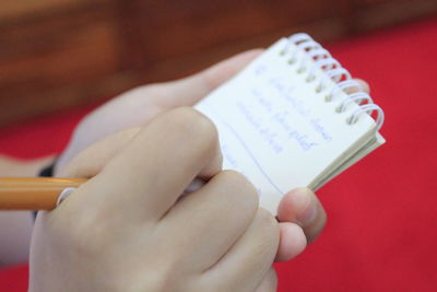 Close-up of hands writing on note pad