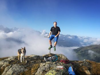 Full length of young man on rock against blue sky