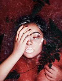 High angle view of sensuous young woman lying in red water