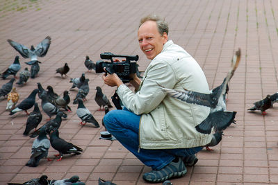 Full length of man photographing birds outdoors