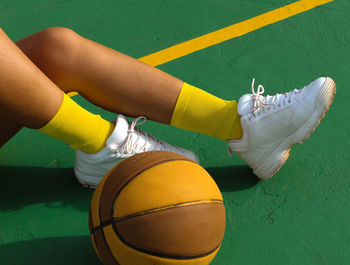 Low section of woman playing basketball on court