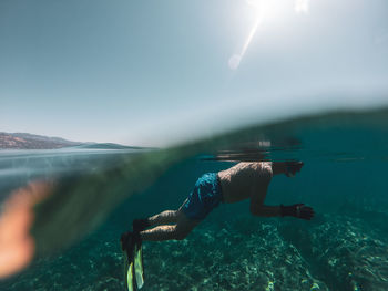 Man swimming in sea against sky