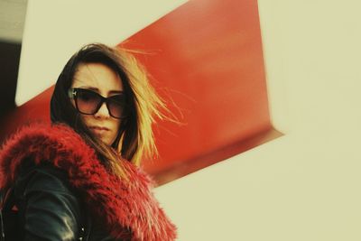 Young woman wearing fur coat against metal