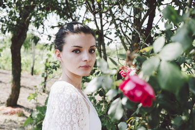 Close-up portrait of young woman standing by tree