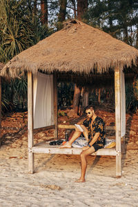Man reading book sitting in cabana on vacation at beach during sunset