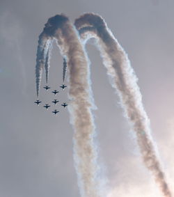 Low angle view of airplanes with trails in flight