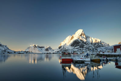 Built structure by lake against clear sky during winter