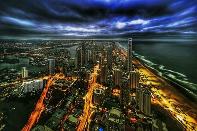 Illuminated cityscape against cloudy sky