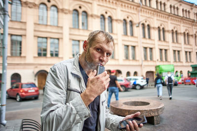 Man holding umbrella on street in city