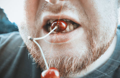 Close-up of man with biting cherry 