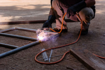 Low section of man welding metal at workshop