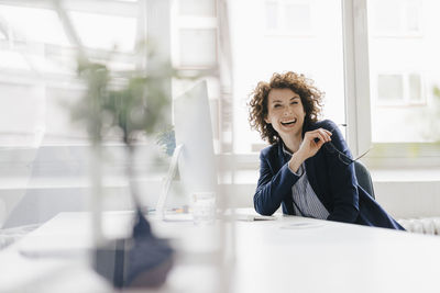 Businesswoman in office sitting at desk, laughing