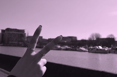 Close-up of hand holding camera against sky