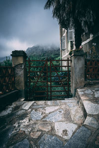 Stone wall by building against sky